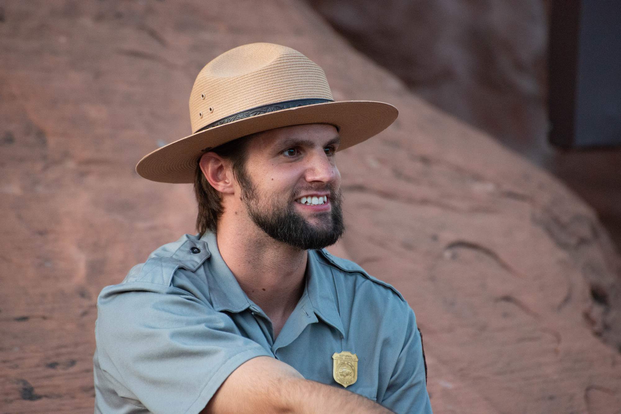 Martin Tow wears a broad brim hat and NPS uniform with shield-shaped badge bearing a bison pinned to his shirt.